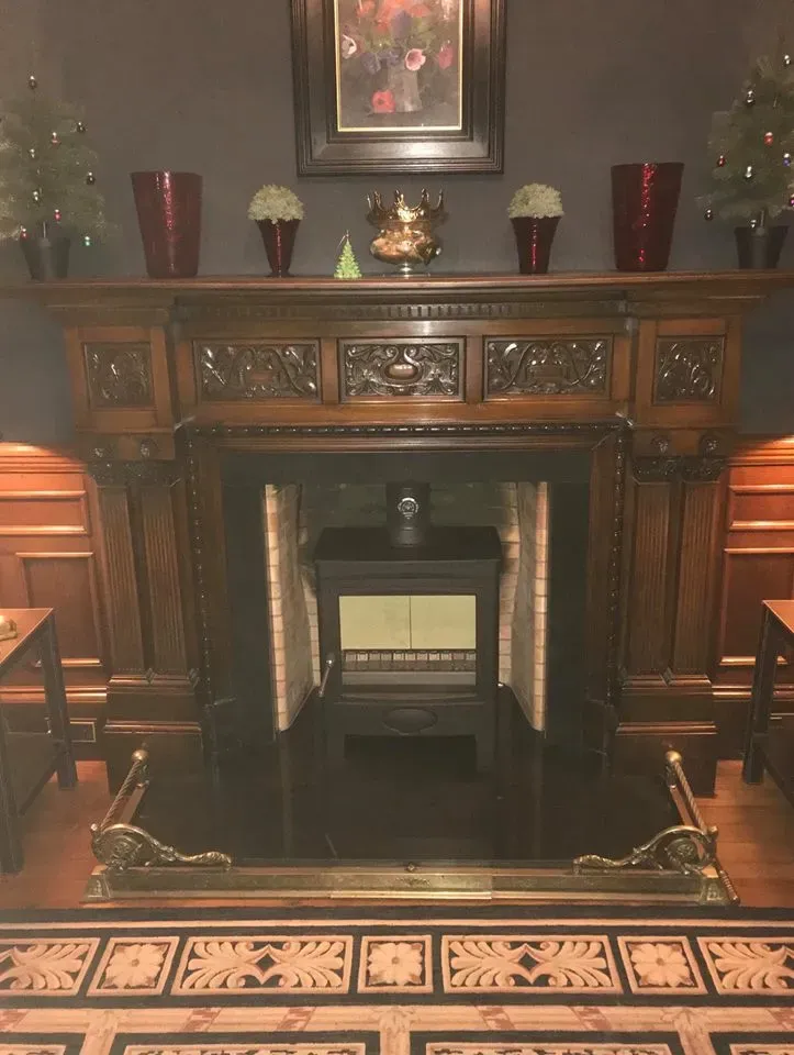Stove fitted in an ornate carved wooden fireplace by Agnew Chimney Engineering Glasgow
