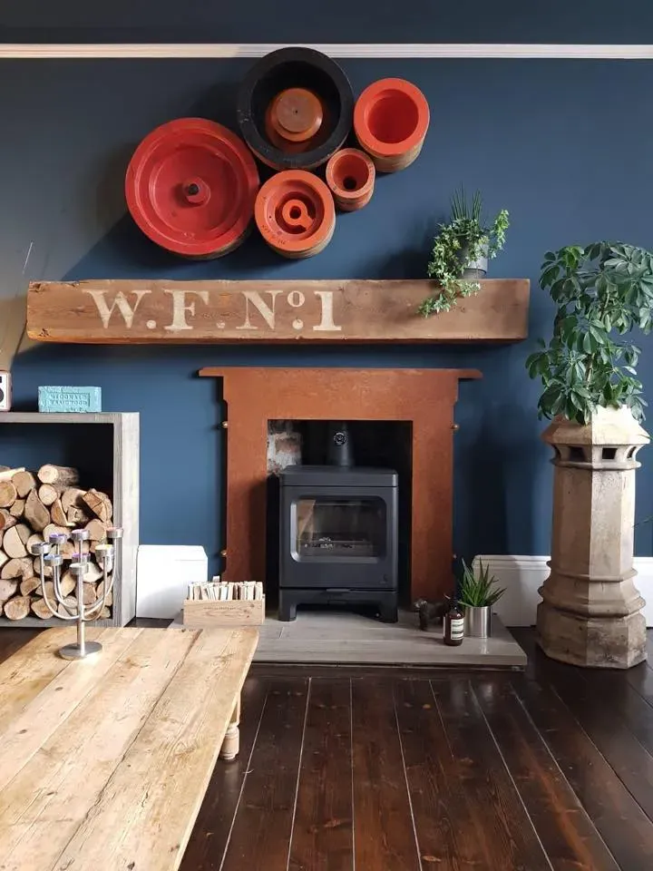 Stove in a copper surround on a blue feature wall by Agnew Chimney Engineering Glasgow