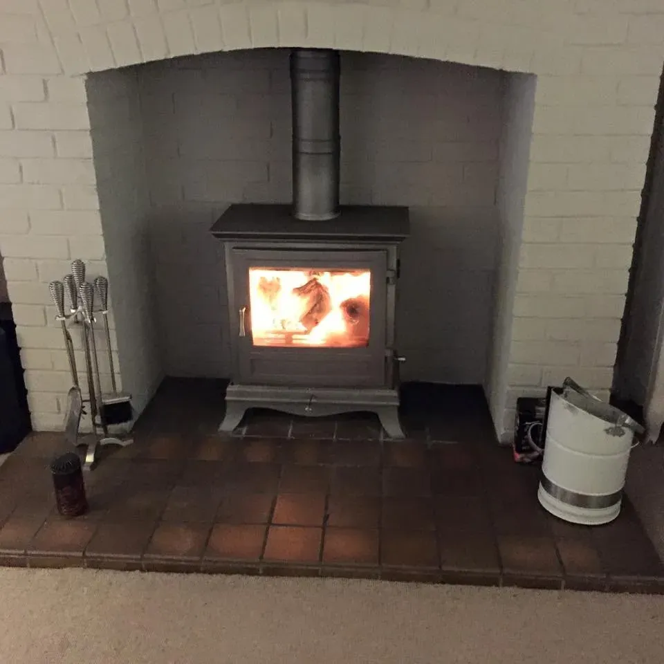 Lit cast iron stove on a tiled hearth by Agnew Chimney Engineering Glasgow