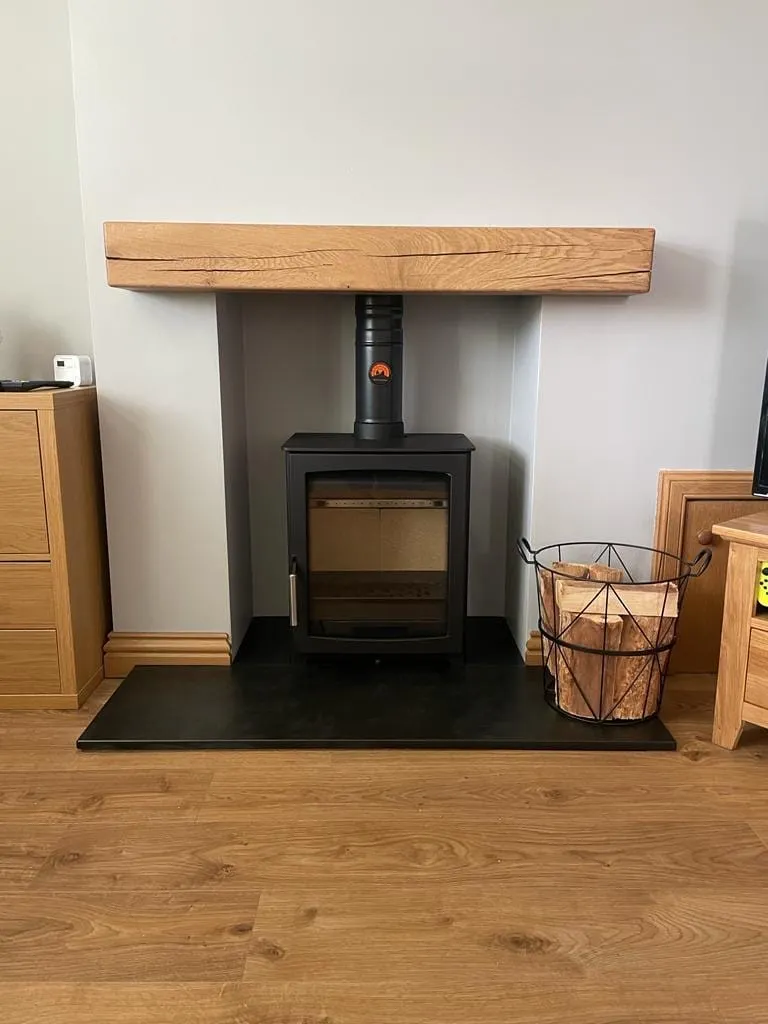 Multi-fuel stove beneath an oak beam with slate hearth by Agnew Chimney Engineering Glasgow