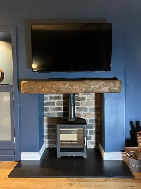 Stove under an oak beam in a brick chimney breast by Agnew Chimney Engineering Glasgow