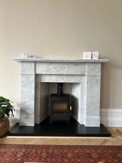 Stove in a light granite fireplace surround by Agnew Chimney Engineering Glasgow